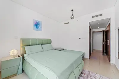 a bedroom with a green bed with a night stand at Lux Retreat with Iconic Burj Khalifa Views in Dubai