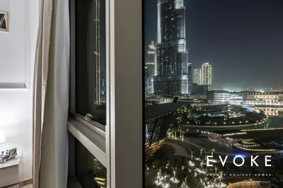 a window with a view of a city at night at Grande Residence Burj View 2 BR by Evoke Luxury in Dubai