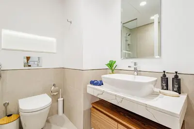 a bathroom with a sink and a toilet and a mirror at Chic Apartment with Balcony & Views in Dubai