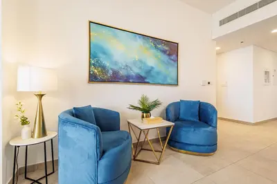 two blue chairs in a room with a painting on the wall at Chic Apartment with Balcony & Views in Dubai