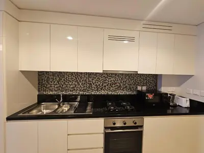 a kitchen with white cabinets and a stove and a sink at Modern New Studio with Panoramic View in Business Bay in Dubai