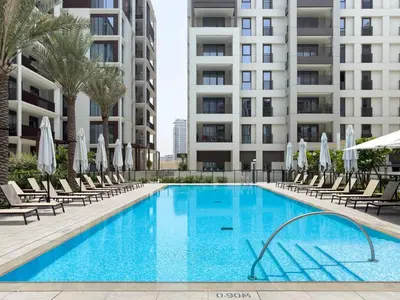 a swimming pool with chairs and umbrellas next to a building at GuestReady - Creek View l 2Bed l Lagoon Escape in Dubai