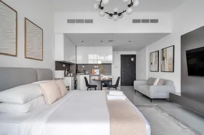 a living room with a white bed and a kitchen at GuestReady - Stylish l High Floor Studio in Dubai