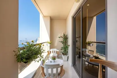 an apartment balcony with a white table and chairs at Luxury 2-Bedroom with Sea & Ain Dubai View in Dubai