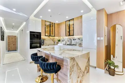 a kitchen with a large island with blue bar stools at Luxury 2-Bedroom with Sea & Ain Dubai View in Dubai