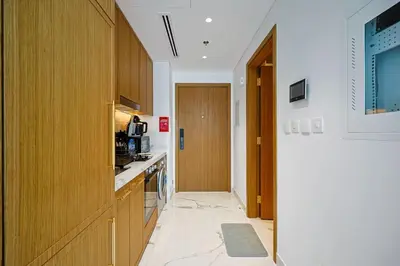 a kitchen with wooden cabinets and a door to a hallway at Spacious Luxury Escape - Modern Comfort in Riviera in Dubai