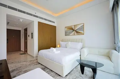 a bedroom with a white bed and a couch and a table at Spacious Luxury Escape - Modern Comfort in Riviera in Dubai