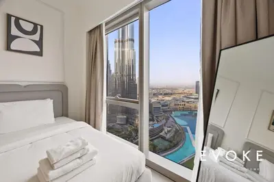a hotel room with a bed and a large window at Grande 2BR Balcony Burj & Fountain Views by Evoke in Dubai