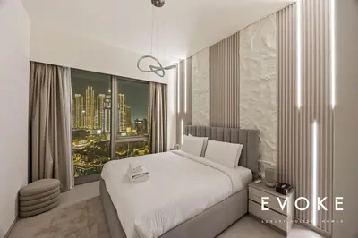 a bedroom with a white bed and a large window at Grande 2BR Balcony Burj & Fountain Views by Evoke in Dubai