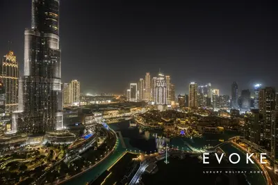 a night view of a city with tall buildings at Grande 2BR Balcony Burj & Fountain Views by Evoke in Dubai