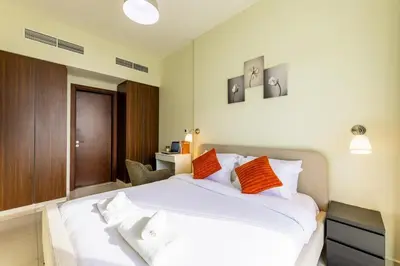 a bedroom with a large white bed with orange pillows at High floor, Canal View, Parking, Crib, Dubai Mall & Burj Khalifa in Dubai