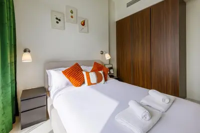a bedroom with a bed with orange and white pillows at High floor, Canal View, Parking, Crib, Dubai Mall & Burj Khalifa in Dubai