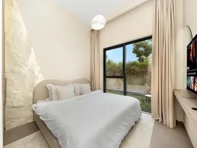 a white bedroom with a bed and a window at Dubai Hills Retreat Garden, Pool & Park Access in Dubai