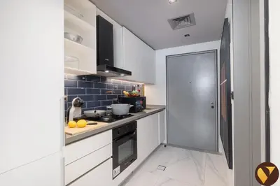 a kitchen with white cabinets and a stove at Vogue Downtown Mag 318 near Burj Khalifa and Dubai Mall, Studio Apartment with Balcony, Canal and City Skyline View, Access to all Amenities in Dubai