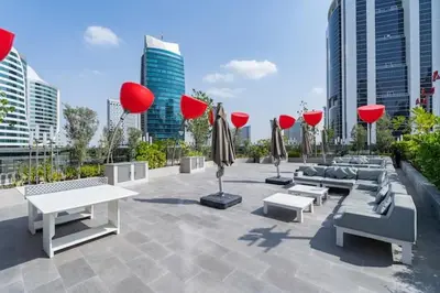 a patio with couches and tables in a city at Vogue Downtown Mag 318 near Burj Khalifa and Dubai Mall, Studio Apartment with Balcony, Canal and City Skyline View, Access to all Amenities in Dubai