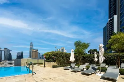 a pool with lounge chairs and umbrellas on a rooftop at Iconic Address 1BR Above Dubai Mall by Maxx value homes in Dubai
