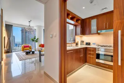 a kitchen with wooden cabinets and a living room at Iconic Address 1BR Above Dubai Mall by Maxx value homes in Dubai