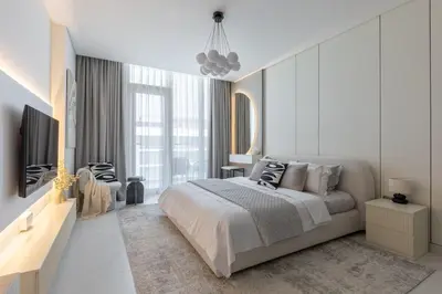 a white bedroom with a large bed and a tv at Designer 3BR Lagoon Views Gym District One in Dubai