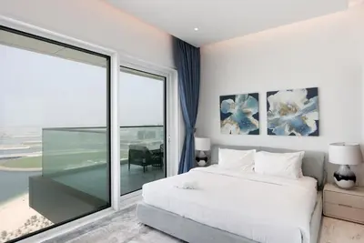 a bedroom with a white bed and a large window at Beachfront 2BR with Maids Room One JBR Sea Palm Ain Atlantis Views in Dubai