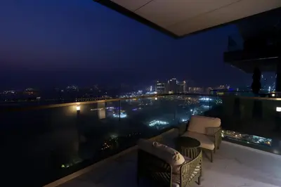 a balcony with a view of a city at night at Beachfront 2BR with Maids Room One JBR Sea Palm Ain Atlantis Views in Dubai