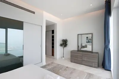 a bedroom with white walls and a large mirror at Beachfront 2BR with Maids Room One JBR Sea Palm Ain Atlantis Views in Dubai