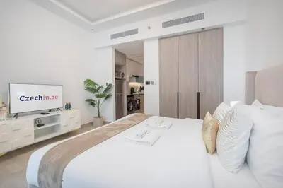 a white bedroom with a white bed and a tv at Chic Studio at ME DO RE Tower Stunning Views in Dubai