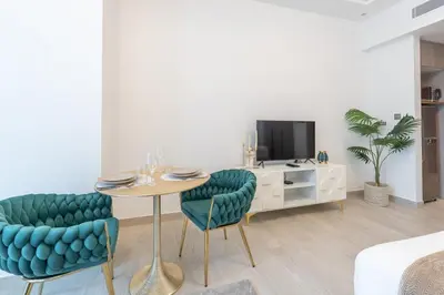 a living room with a table and chairs and a tv at Chic Studio at ME DO RE Tower Stunning Views in Dubai