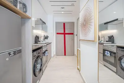 a large kitchen with a red door in it at Chic Studio at ME DO RE Tower Stunning Views in Dubai