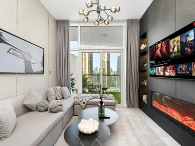 a living room with a couch and a tv at Stunning Burj Khalifa & Lake View 2BR with GYM and Pool in Dubai