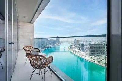 a balcony with two chairs and a view of a river at Elegant 2 M with Direct Canal & Iconic View in Dubai