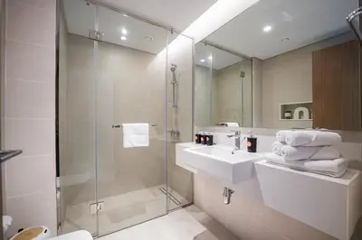 a bathroom with a shower and a sink and a mirror at Elegant 2 M with Direct Canal & Iconic View in Dubai