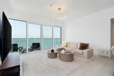 a white living room with a couch and a tv at Luxury 2BR with Panoramic Sea View Private Beach in Dubai