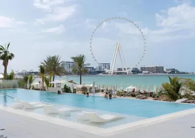 a swimming pool with a view of the ferris wheel at Luxury 2BR with Panoramic Sea View Private Beach in Dubai