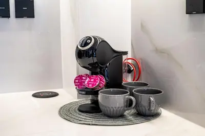 a coffee maker sitting on a counter with three cups at Burj Khalifa View-Beautiful Pool-Gym-Business Bay in Dubai