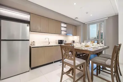 a kitchen with a table with chairs and a refrigerator at BURJ CROWN - Elegant & Spacious Two-Bedroom Apartment in Downtown Dubai, Just 10 Minutes' Walk from Dubai Mall & Dubai Fountains, Surrounded by Iconic Landmarks in Dubai