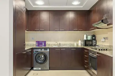 a kitchen with wooden cabinets and a washing machine at Silkhaus Luxury Studio at Sky Gardens in DIFC Views in Dubai