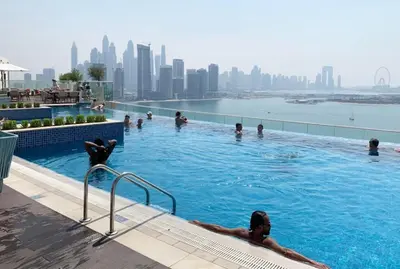 a group of people swimming in a swimming pool with a city skyline at Spacious 1 bed with seaview in Seven Palm - Palm Jumeirah - IQPRO Holidays in Dubai