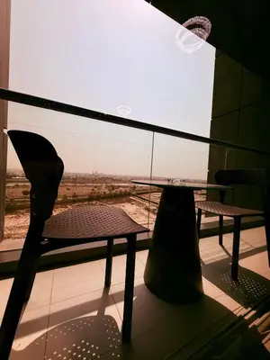 a table and a chair in front of a window at Spacious Luxury Lagoon View 2Bhk in Dubai