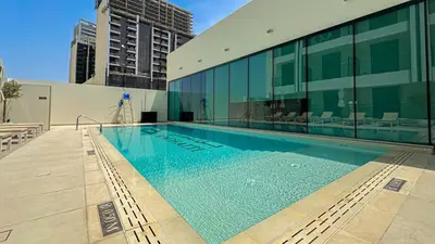 a swimming pool in front of a building at Welhome - Modern Gold Accents Studio in JVC with Balcony in Dubai
