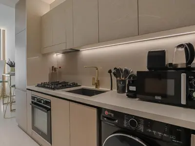 a kitchen with a sink and a stove and a microwave at Welhome - Modern Gold Accents Studio in JVC with Balcony in Dubai