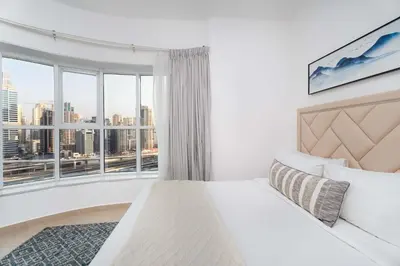 a bedroom with a white bed and a large window at Modern 1BR with City View - Balcony - Near Metro in Dubai