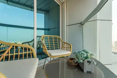 a balcony with a chair and a glass table at Modern 1BR with City View - Balcony - Near Metro in Dubai