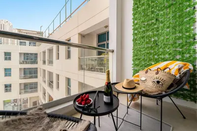 a balcony with a table with a bottle of champagne and a hat at Inviting Dubai Marina Studio near Beach and Canal in Dubai