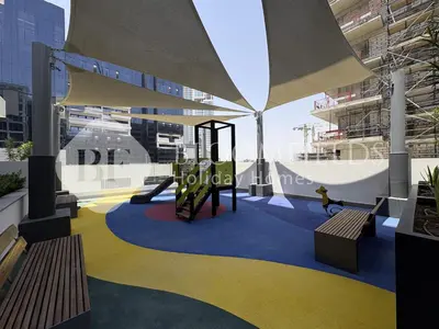 a playground in the middle of a building with benches at Bloomfields Supreme Stu In Azizi Riviera in Dubai