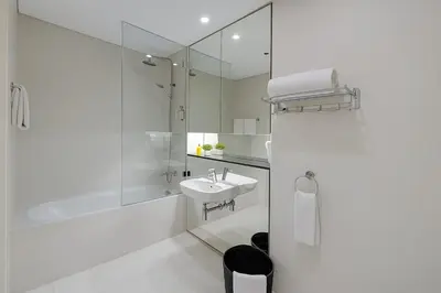 a white bathroom with a sink and a shower at DIFC Index Tower Burj Khalifa View 1BR in Dubai