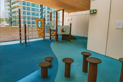 a room with a playground with a slide and stools at Serene Ocean Views 2BR Emaar Beachfront in Dubai