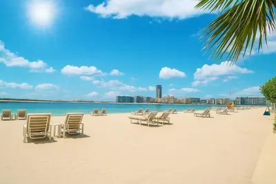 a beach with chairs and the ocean and a city at Serene Ocean Views 2BR Emaar Beachfront in Dubai