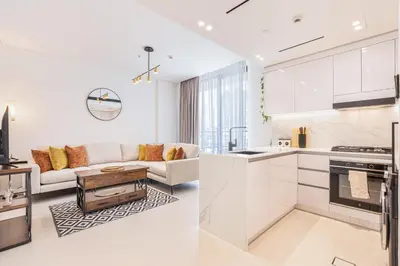 a white kitchen and living room with a couch at Serene and Stylish Home in the Heart of JVC in Dubai