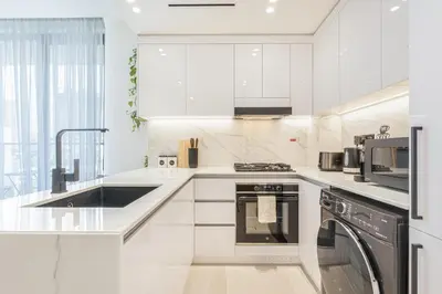 a white kitchen with a sink and a dishwasher at Serene and Stylish Home in the Heart of JVC in Dubai