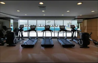 a gym with several treadmills and a swimming pool at Luxury Studio with Pool, Gym & Downtown Access in Dubai